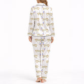White pajama set with short sleeve button down top and shorts, featuring a playful pattern of cartoon dachshund dogs, some holding blue martini glasses, and the word 'GOOD' stylized as a dog, with green piping.