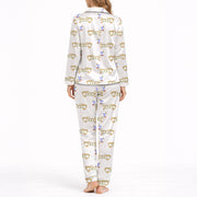White pajama set with short sleeve button down top and shorts, featuring a playful pattern of cartoon dachshund dogs, some holding blue martini glasses, and the word 'GOOD' stylized as a dog, with green piping.