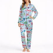 Women's pajama set with whimsical Eastern charm pattern featuring green dragons, pink dragons, peacocks, Mahjong tiles, and 'Charleston' text on a light blue background.
