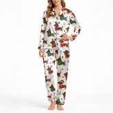 A woman wearing a white short sleeve pajama set with shorts, featuring a festive Christmas pattern of cartoon dachshunds dressed as Santa, reindeer, and Christmas trees. The pajamas have red piping.