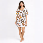 Women's white pajama set with a vibrant autumn-themed print featuring pumpkins, fall leaves, coffee mugs, sweaters, footballs, and cozy fall phrases, perfect for cooler weather.