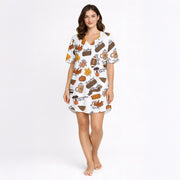 Women's white pajama set with a vibrant autumn-themed print featuring pumpkins, fall leaves, coffee mugs, sweaters, footballs, and cozy fall phrases, perfect for cooler weather.