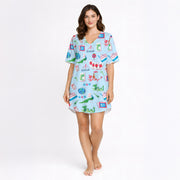 Women's pajama set with whimsical Eastern charm pattern featuring green dragons, pink dragons, peacocks, Mahjong tiles, and 'Charleston' text on a light blue background.