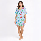 Women's pajama set with whimsical Eastern charm pattern featuring green dragons, pink dragons, peacocks, Mahjong tiles, and 'Charleston' text on a light blue background.