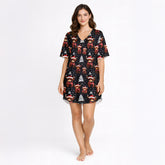 Women's Christmas pajama set featuring a festive pattern of cute Highland cows wearing Santa hats and plaid scarves, with white Christmas trees and snowflakes on a black background. The set includes a short-sleeve button-down top and matching shorts.