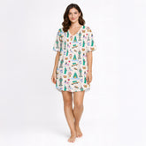 Women's pajama set featuring a whimsical global city print with landmarks like the Statue of Liberty, Empire State Building, Big Ben, and Eiffel Tower, along with urban elements like taxis, pretzels, and coffee cups, on a white background.