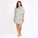 Women's pajama set featuring a whimsical global city print with landmarks like the Statue of Liberty, Empire State Building, Big Ben, and Eiffel Tower, along with urban elements like taxis, pretzels, and coffee cups, on a white background.