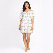 White pajama set with short sleeve button down top and shorts, featuring a playful pattern of cartoon dachshund dogs, some holding blue martini glasses, and the word 'GOOD' stylized as a dog, with green piping.