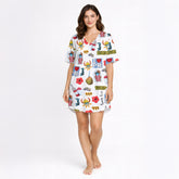 Woman wearing a white long-sleeve button-down pajama set with a colorful, all-over print featuring Puerto Rican cultural symbols like the flag, Coqui frog, Vejigante mask, and 'I love PR' text. The pajamas are made of soft knit fabric.