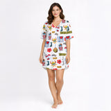 Woman wearing a white long-sleeve button-down pajama set with a colorful, all-over print featuring Puerto Rican cultural symbols like the flag, Coqui frog, Vejigante mask, and 'I love PR' text. The pajamas are made of soft knit fabric.