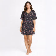 Women's short sleeve button down pajama set with shorts featuring a dark celestial and botanical print of moths, crescent moons, and pink flowers on a black background.