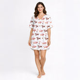 Women's pajama set with a playful white background print featuring various brown dachshund dogs wearing accessories and pink-stemmed martini glasses.