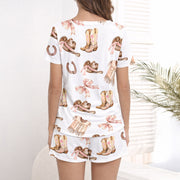 Women's pajama set featuring a charming Western-themed watercolor pattern with cowboy boots, hats, vests, horseshoes, and pink plaid bows on a white background.