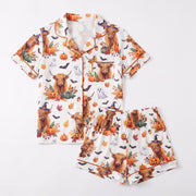 Highland cow Halloween pajama set for women – short sleeve button-down top and shorts with pumpkins, ghosts and bats on ivory knit, front flat lay