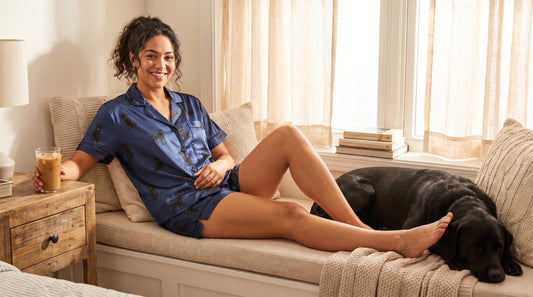 Woman wearing black lab print summer pajama set relaxing at home with her dog