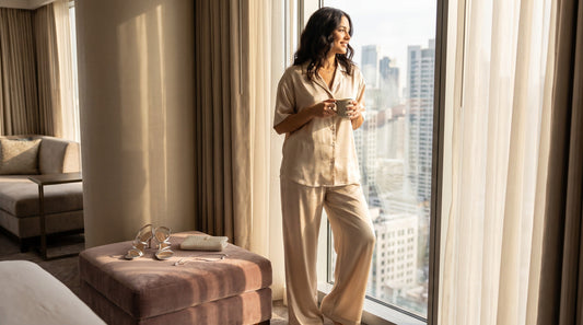 Woman wearing elegant satin two-piece set for summer wedding guest outfit in bright hotel suite