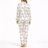 White pajama set with short sleeve button down top and shorts, featuring a playful pattern of cartoon dachshund dogs, some holding blue martini glasses, and the word 'GOOD' stylized as a dog, with green piping.