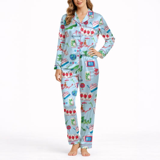 Women's pajama set with whimsical Eastern charm pattern featuring green dragons, pink dragons, peacocks, Mahjong tiles, and 'Charleston' text on a light blue background.