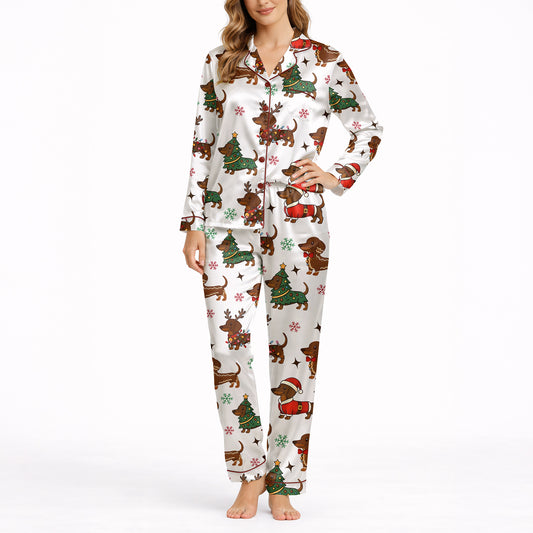 A woman wearing a white short sleeve pajama set with shorts, featuring a festive Christmas pattern of cartoon dachshunds dressed as Santa, reindeer, and Christmas trees. The pajamas have red piping.