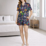Women's pajama set with a vibrant Caribbean-themed pattern featuring Coquí frogs, Salsa hearts, Puerto Rico flag, coffee and rum drinks, palm trees, and cameras on a dark blue background.