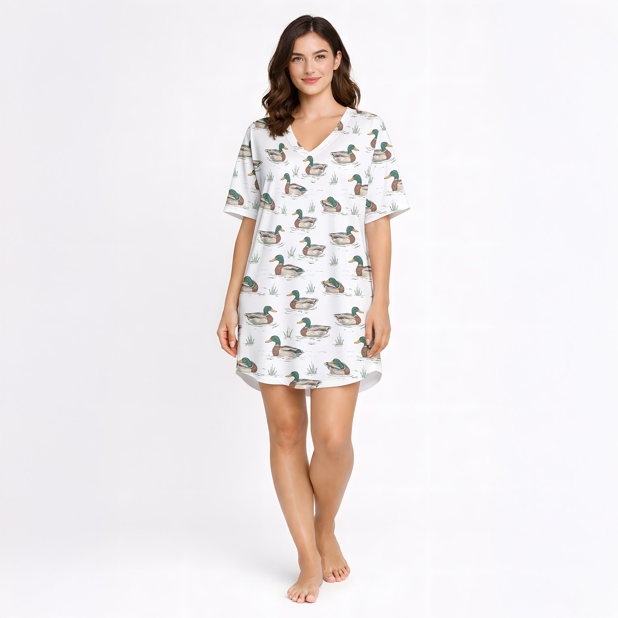 Women's pajama set with short sleeves and shorts, featuring a repeating pattern of mallard ducks swimming in water with green grass, trimmed with green piping. The fabric is a soft, light-colored knit.