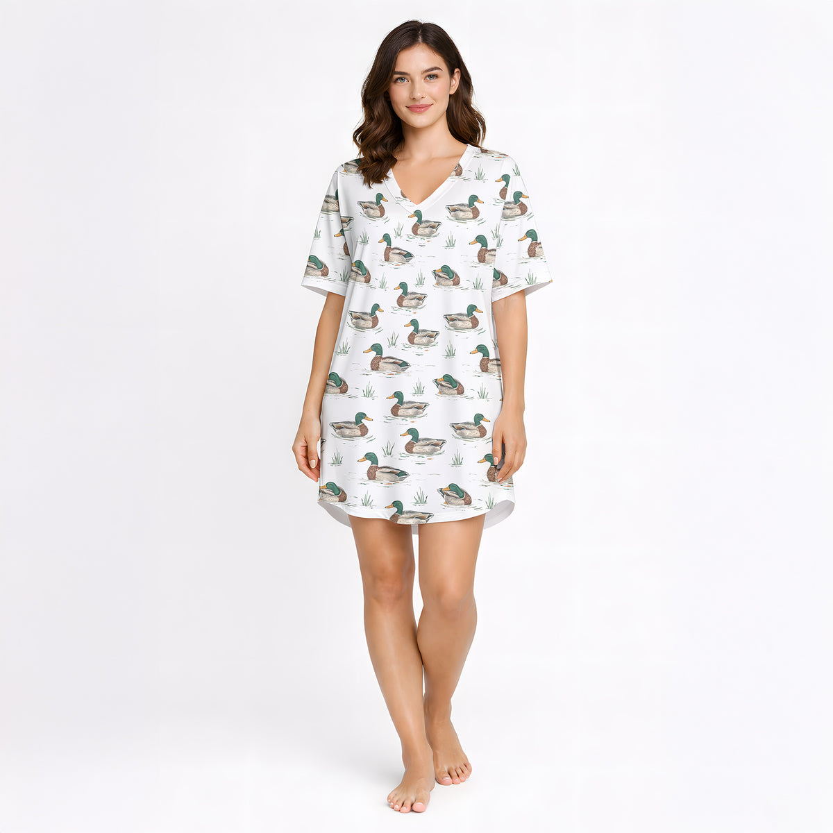 Women's pajama set with short sleeves and shorts, featuring a repeating pattern of mallard ducks swimming in water with green grass, trimmed with green piping. The fabric is a soft, light-colored knit.
