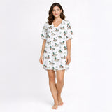 Women's pajama set with short sleeves and shorts, featuring a repeating pattern of mallard ducks swimming in water with green grass, trimmed with green piping. The fabric is a soft, light-colored knit.