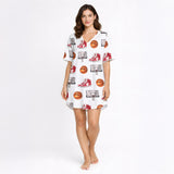 Woman wearing a white short sleeve button-down pajama set with red piping, featuring a fun basketball, sneaker, and hoop pattern.