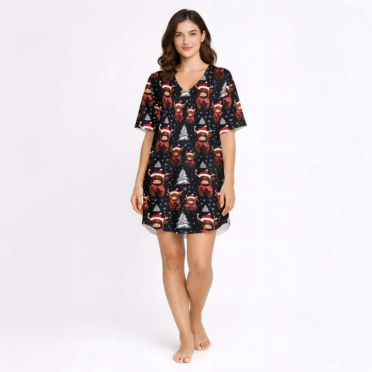 Women's Christmas pajama set featuring a festive pattern of cute Highland cows wearing Santa hats and plaid scarves, with white Christmas trees and snowflakes on a black background. The set includes a short-sleeve button-down top and matching shorts.