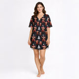 Women's Christmas pajama set featuring a festive pattern of cute Highland cows wearing Santa hats and plaid scarves, with white Christmas trees and snowflakes on a black background. The set includes a short-sleeve button-down top and matching shorts.