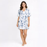 Women's pajama set with a blue sketch-style pattern of horses, horseshoes, and saddles on a white background, made from soft knit fabric.