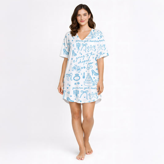 Woman wearing a white and light blue wedding-themed pajama set with short sleeves and shorts, holding a white mug. The pajama set features doodles of wedding cakes, rings, doves, and text 'going to the chapel' and 'gonna get married'.