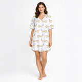 White pajama set with short sleeve button down top and shorts, featuring a playful pattern of cartoon dachshund dogs, some holding blue martini glasses, and the word 'GOOD' stylized as a dog, with green piping.
