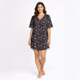 Women's short sleeve button down pajama set with shorts featuring a dark celestial and botanical print of moths, crescent moons, and pink flowers on a black background.