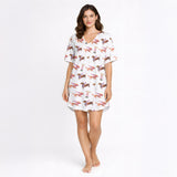 Women's pajama set with a playful white background print featuring various brown dachshund dogs wearing accessories and pink-stemmed martini glasses.
