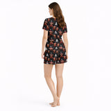 Women's Christmas pajama set featuring a festive pattern of cute Highland cows wearing Santa hats and plaid scarves, with white Christmas trees and snowflakes on a black background. The set includes a short-sleeve button-down top and matching shorts.